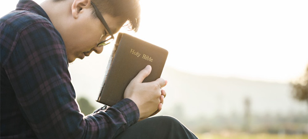 man holds a bible while praying for guidance and wisdom on his calling