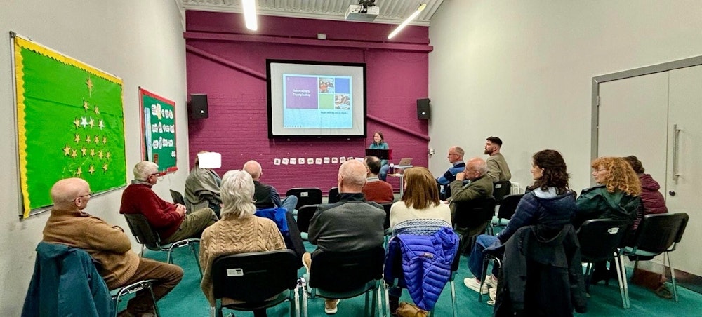 A group gather to listen to an event run by MAP and Welcome Churches