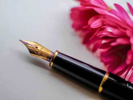 A fancy pen for signing a will, accompanied by two pink flowers