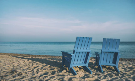 Two blue deck chairs on the beach facing the sea, waiting for a pension scheme recipient