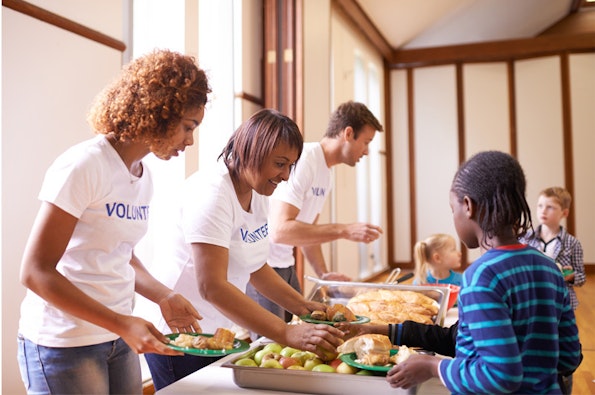 A diverse group of volunteers provide food for children.