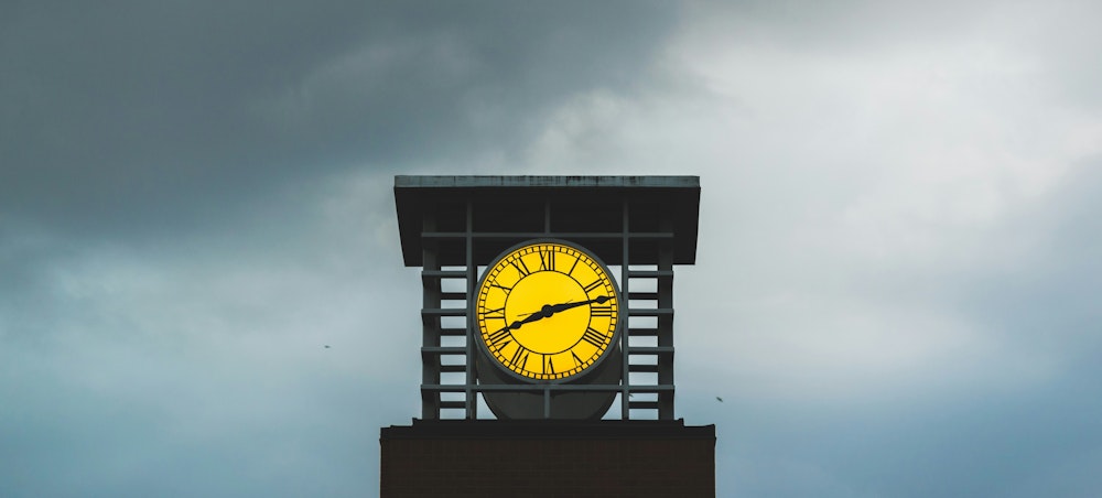 An illuminated clock tower highlighted against a stormy sky.