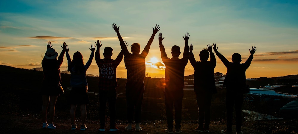 A group of young people celebrate, while looking into the sunset