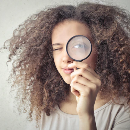 A woman looks at the camera through a magnifying glass